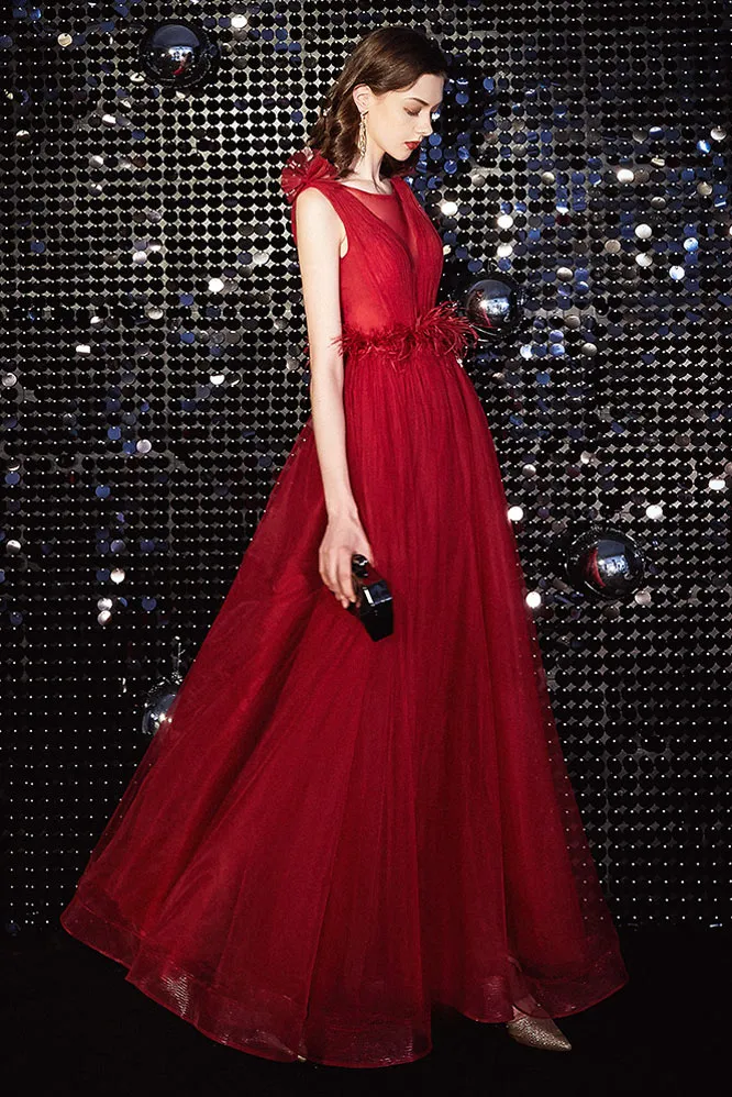 Robe de bal rouge rubis en tulle décolleté plongeant ceinturé de plume